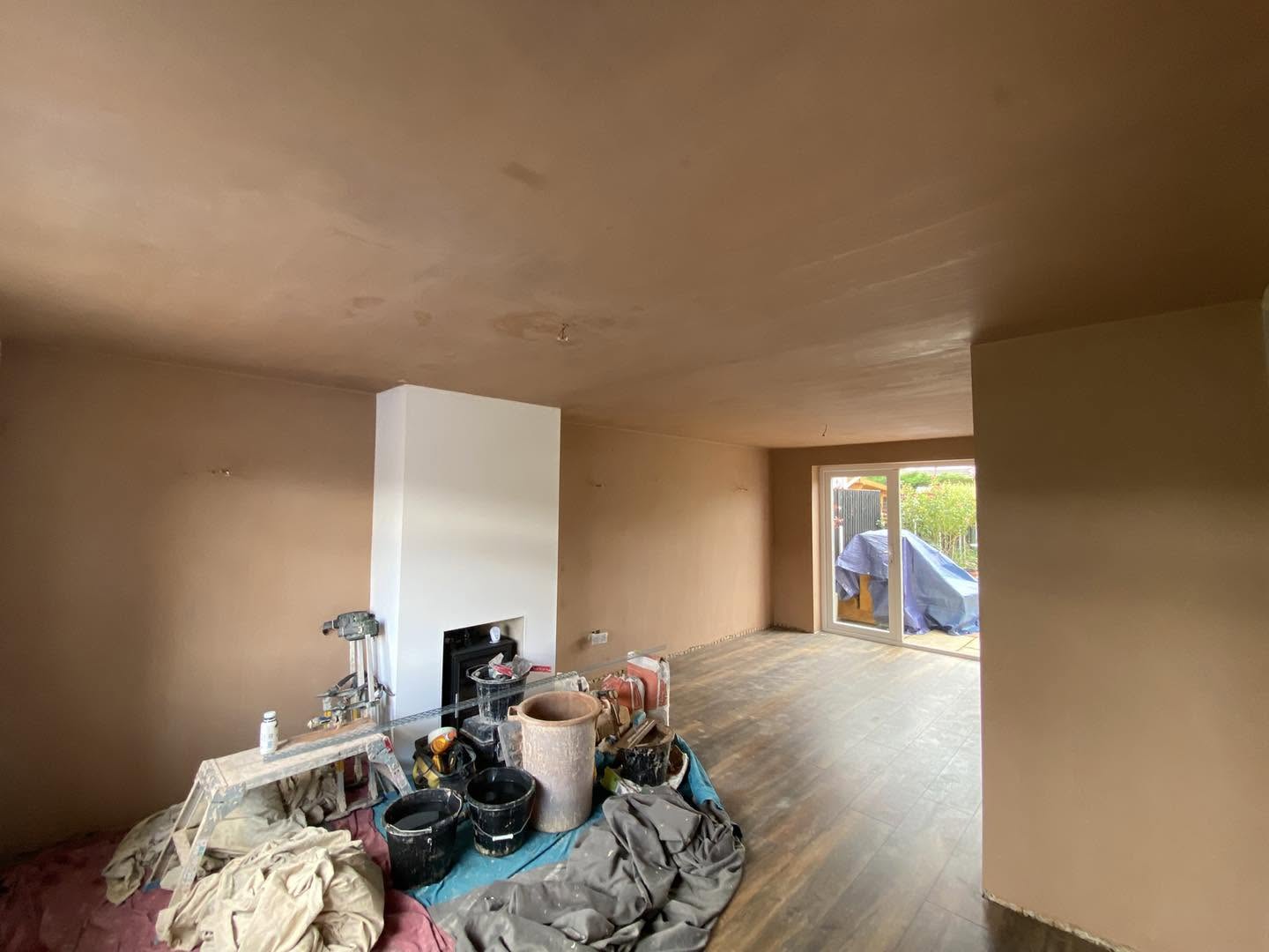 The same living room from the other end, buckets and tools by the patio doors