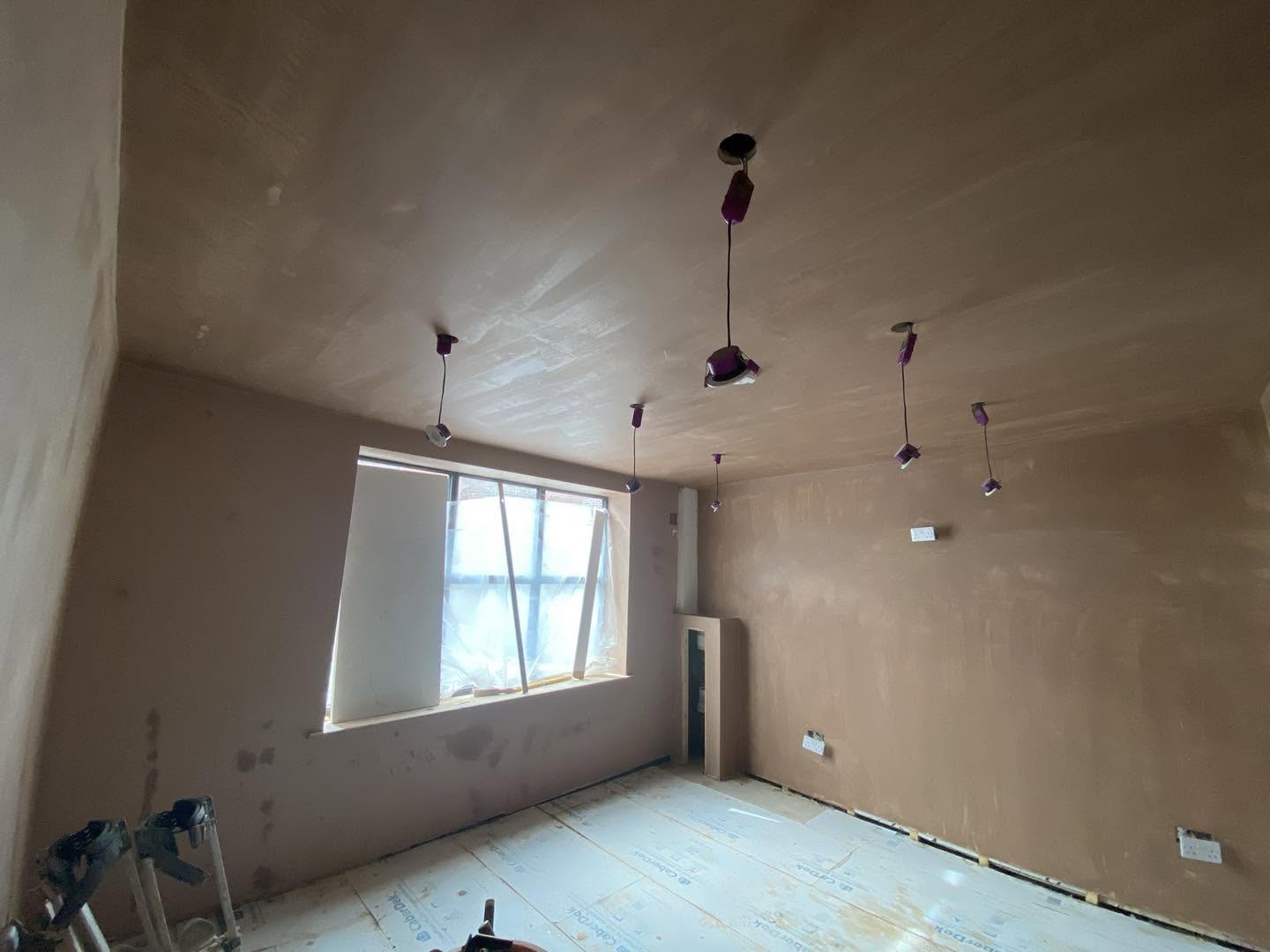 A room freshly skimmed, walls and ceiling, with pendant wires and a window