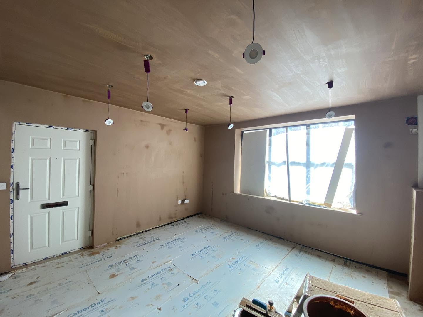 The same room by the white front door, fresh plaster all round