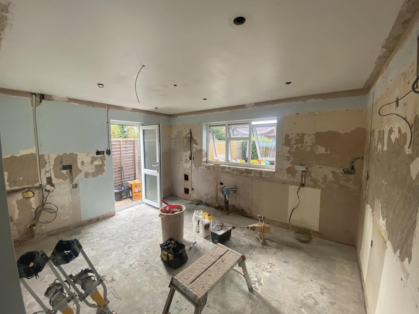 The same room with its walls hacked off, a trestle and buckets on the floor