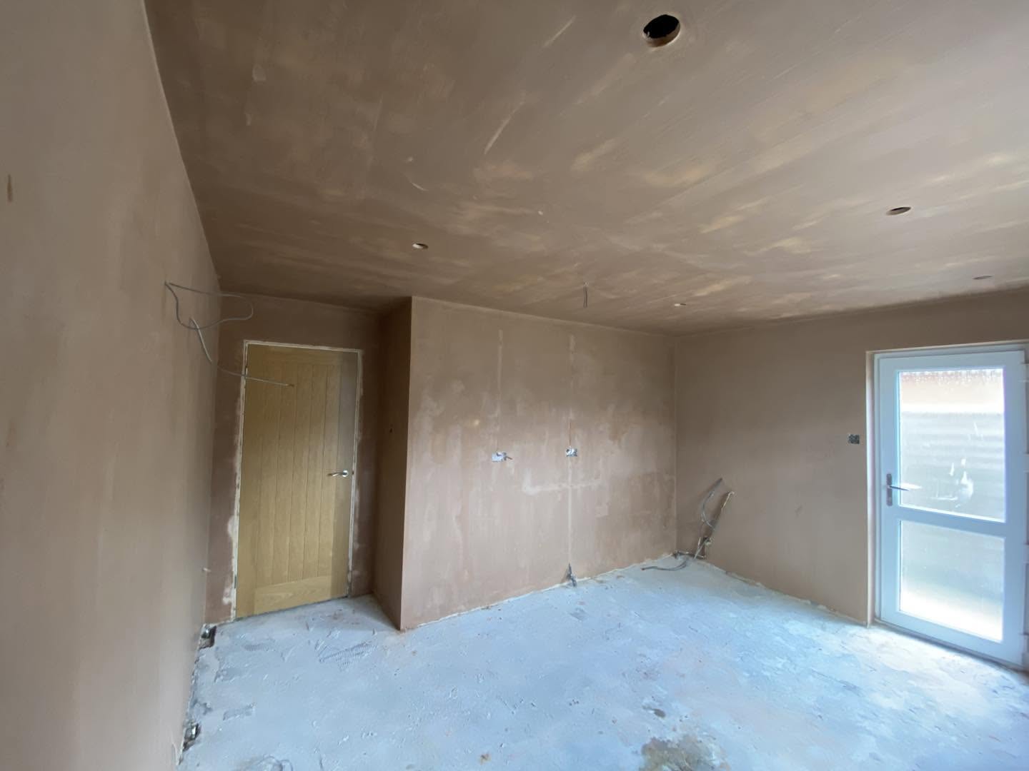 The same room freshly skimmed, with an oak door and the back door