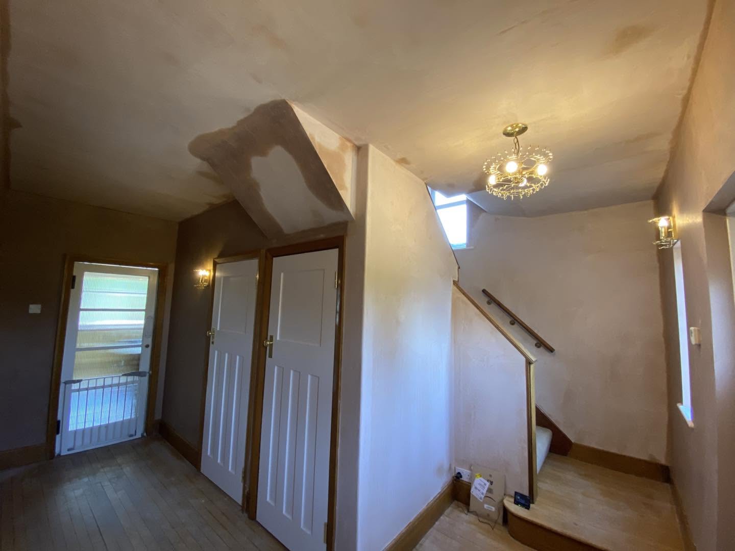 Hall and staircase freshly plastered, a chandelier and the front door