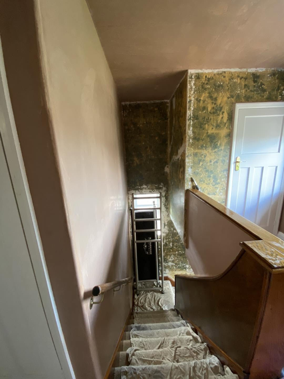 The staircase during the work, treads protected, old wallpaper still on the far wall