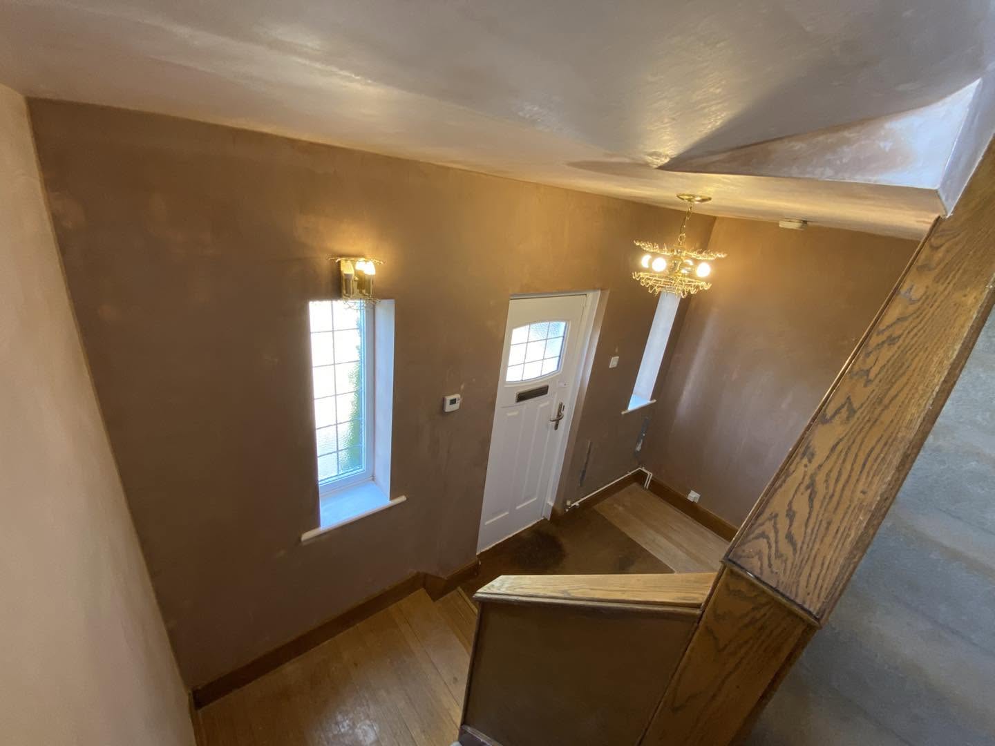 The hall from the stairs, fresh plaster, wall lights and the front door