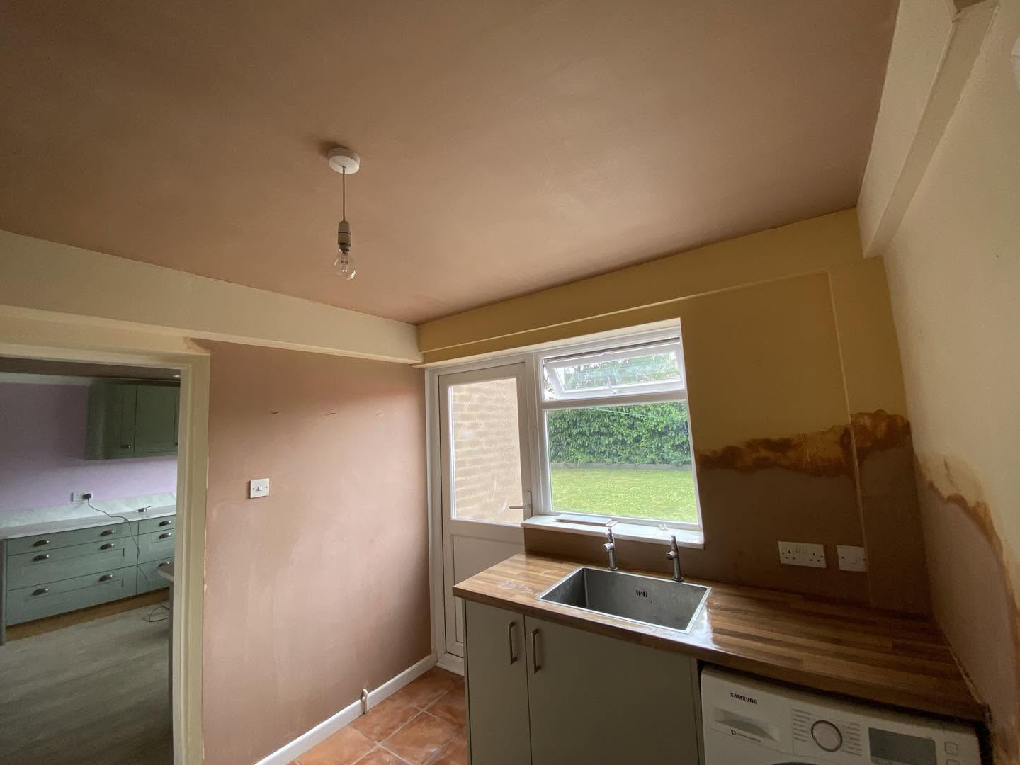 Kitchen walls and ceiling freshly plastered, sink and back door