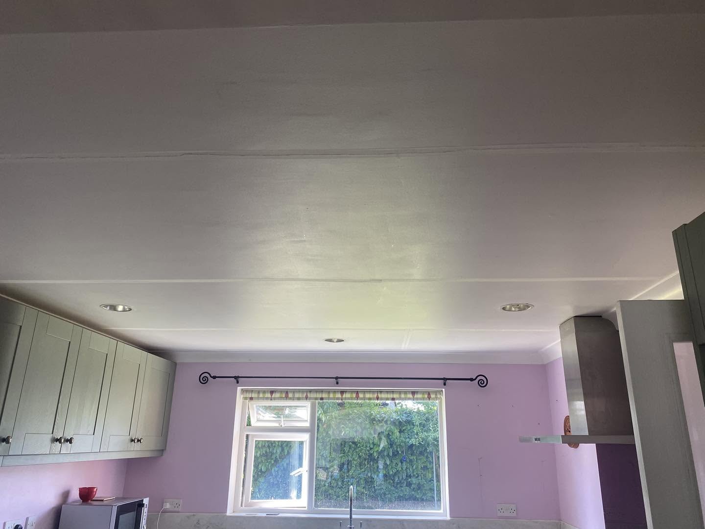 A kitchen ceiling freshly skimmed above sage green cabinets