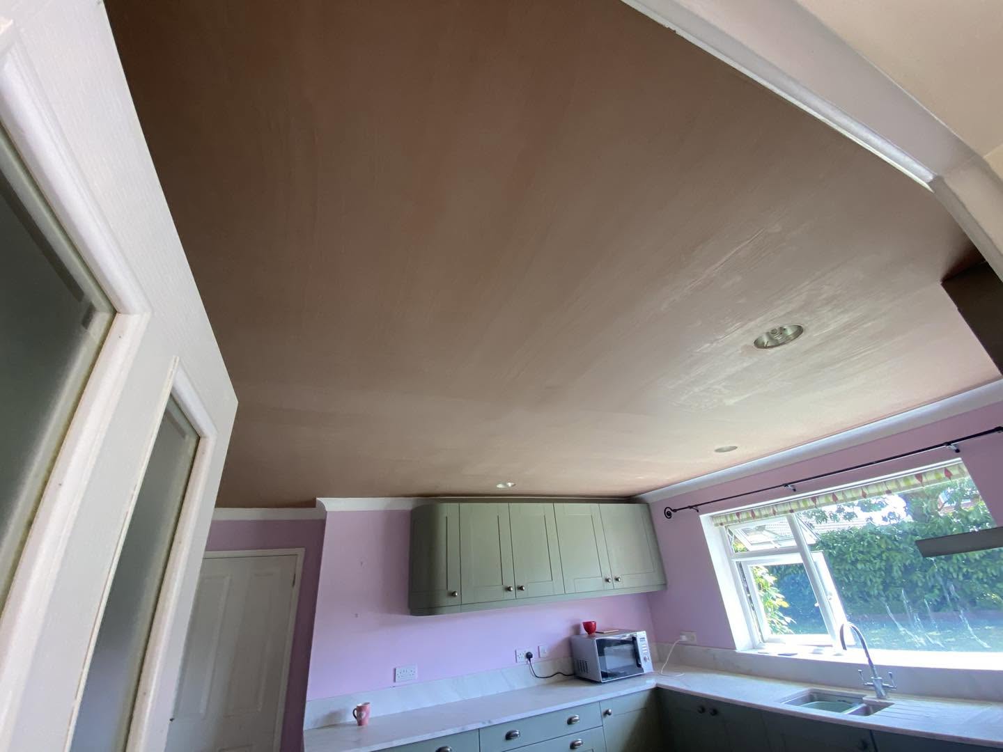A kitchen ceiling skimmed above wall cabinets and a window