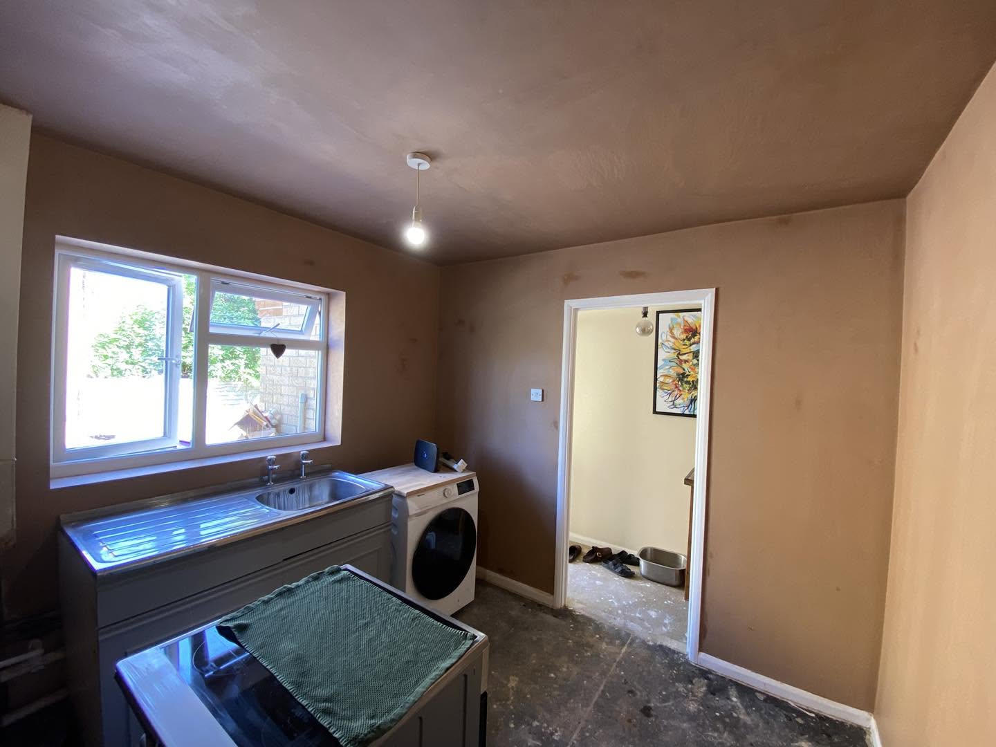The kitchen walls freshly plastered around the window and doorway