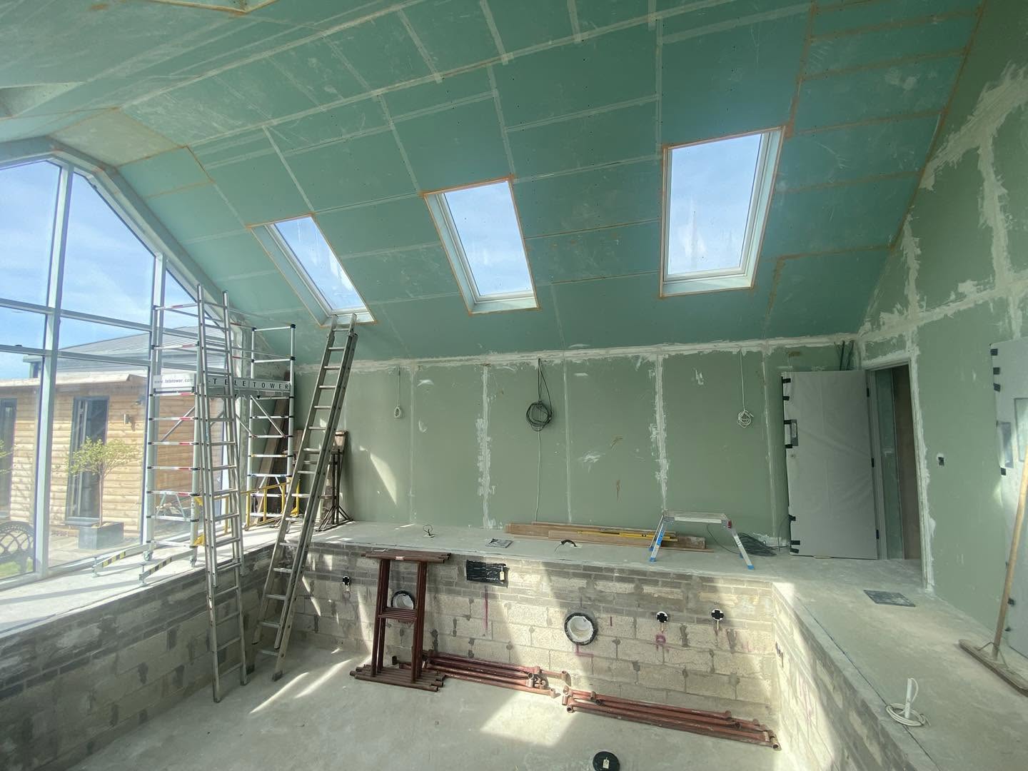 A loft conversion boarded out in green moisture board, gable glazing and step ladders
