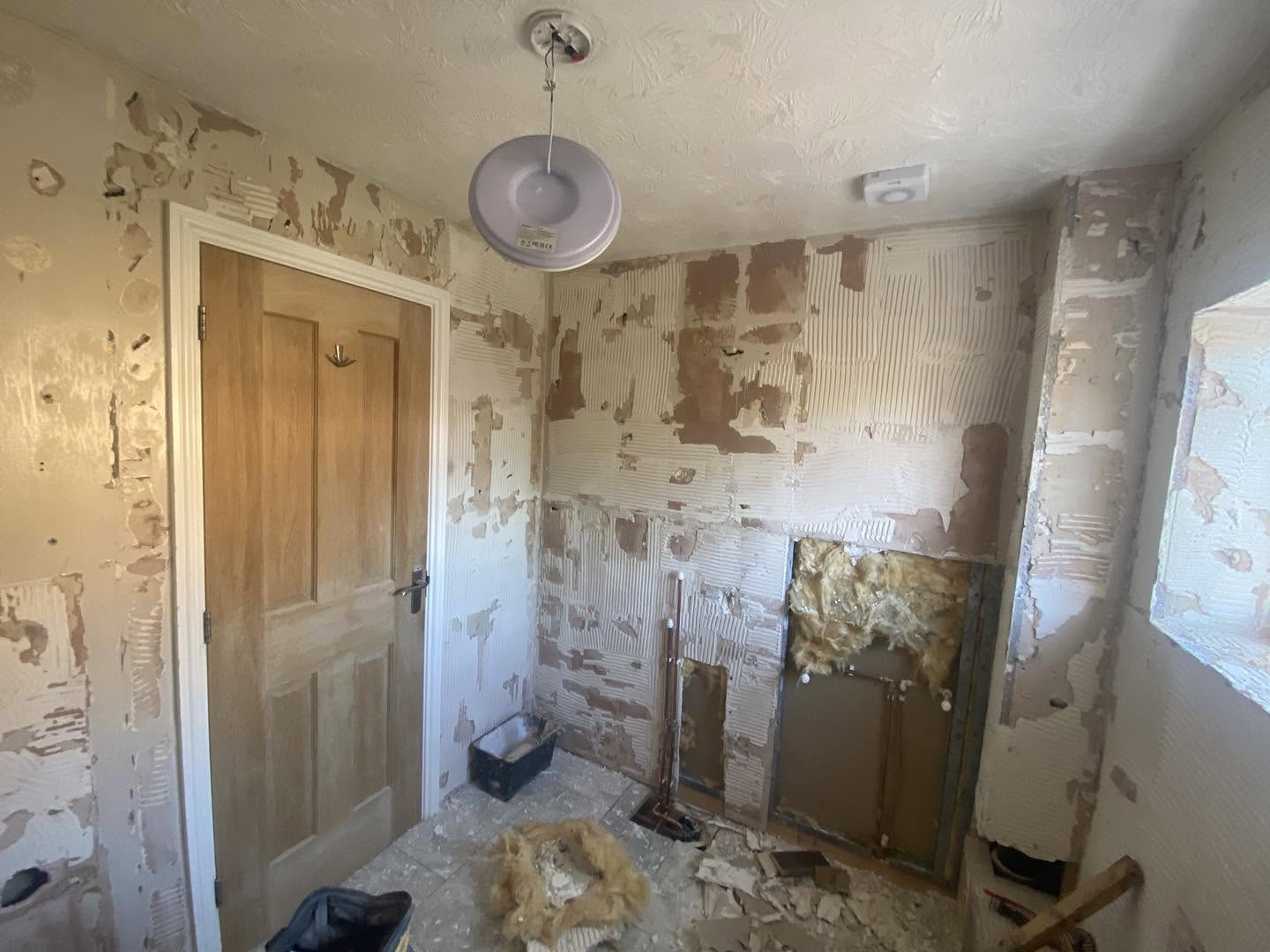 A small room with its walls stripped and patched, insulation on the floor