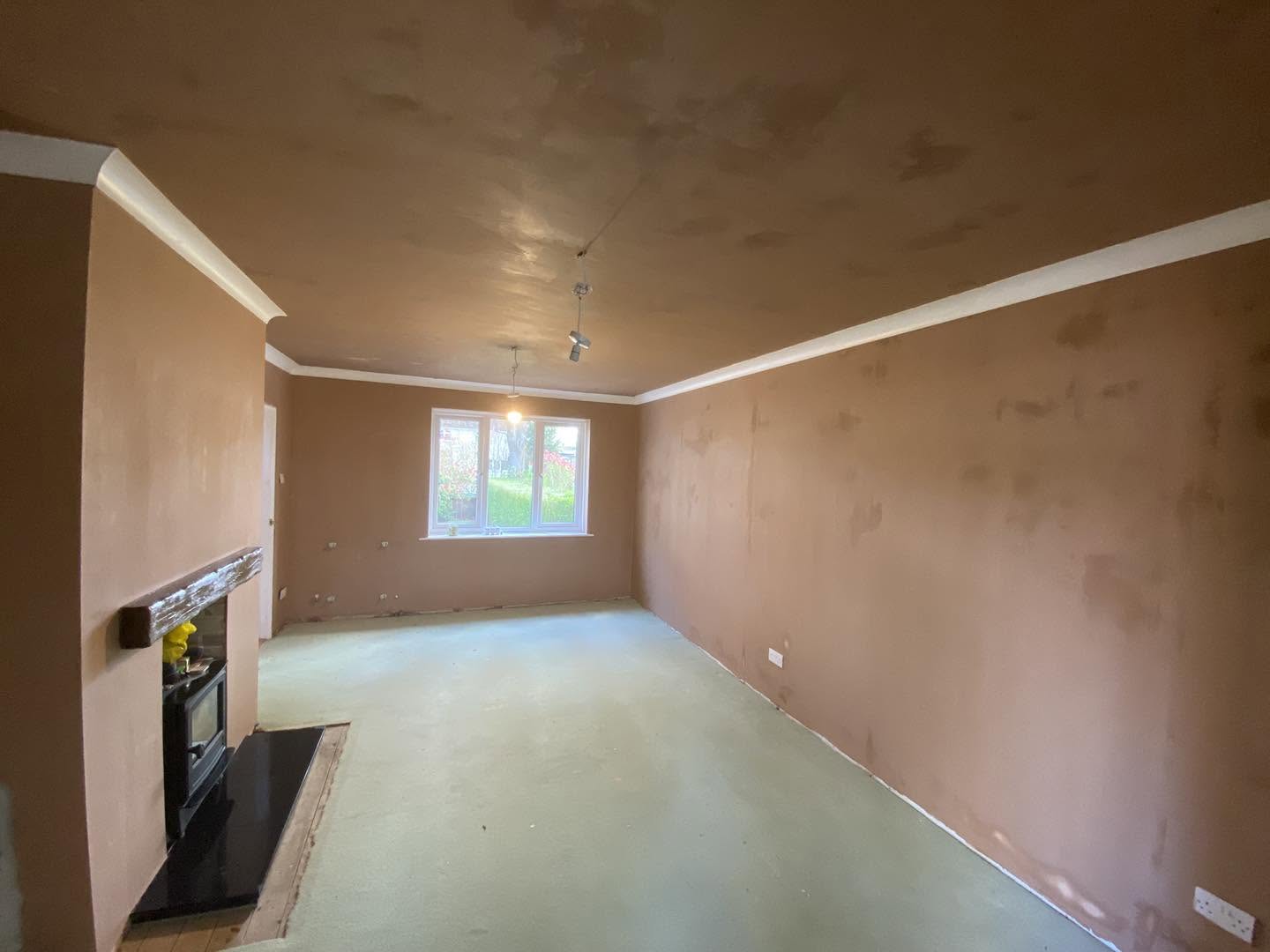 The same living room with its walls and ceiling freshly skimmed, fireplace and coving