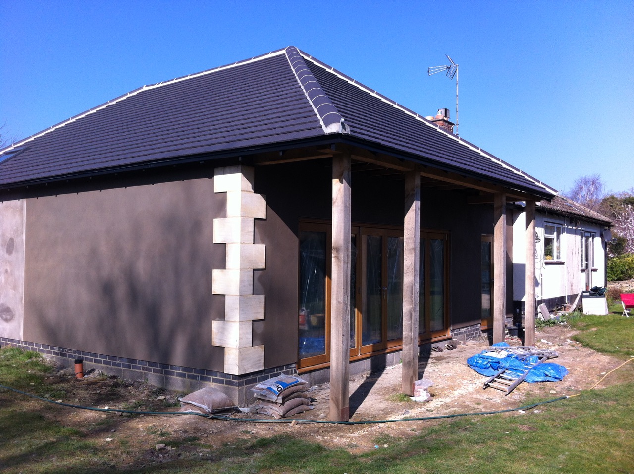 A rendered bungalow extension with stone quoins, seen from the garden