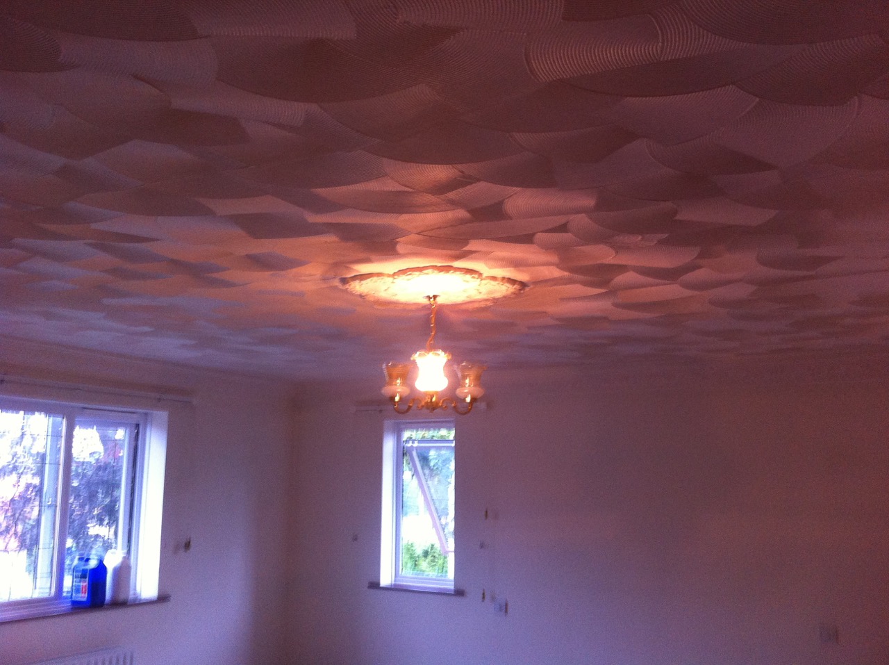 A swirled Artex ceiling around a chandelier