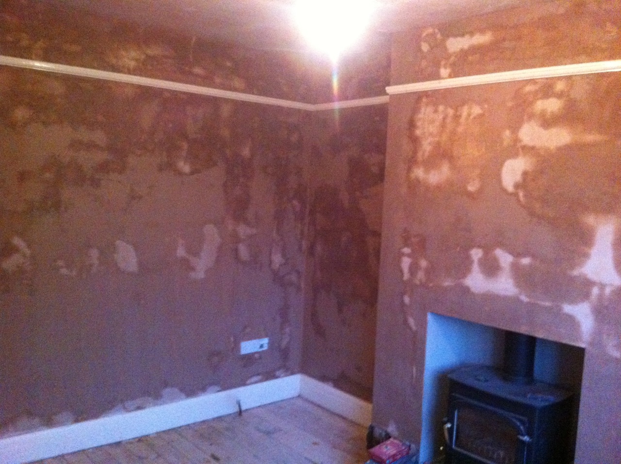 A room with its walls hacked off and patched around a wood burner